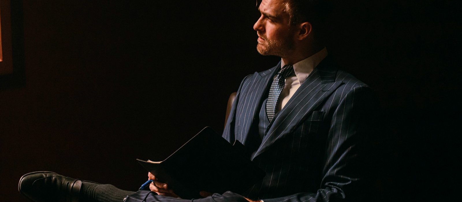 a man in a suit sitting in a dark room