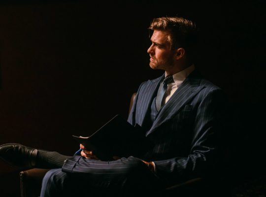 a man in a suit sitting in a dark room