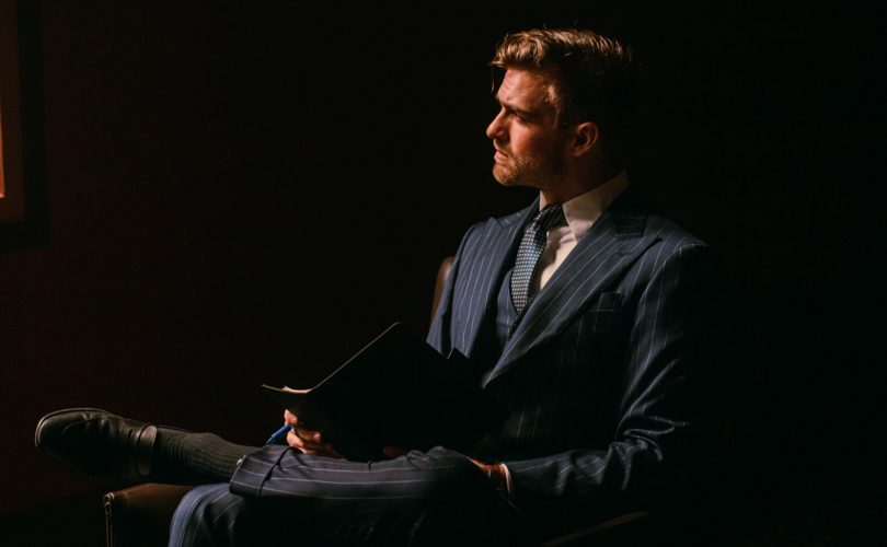 a man in a suit sitting in a dark room